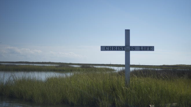 A cross stands tall in the marsh on Tangier Island.