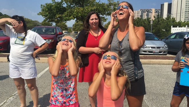 Elizabeth Werner and her two daughters, Vivian, left, and Avalyn, view the eclipse at the Worcester County Library in Ocean City on Monday, Aug. 21.