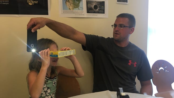 Todd Kuhns and his daughter, Alivia, 8, test out a homemade eclipse pinhole they made at the Worcester County Library in Ocean City on Monday, Aug. 21.