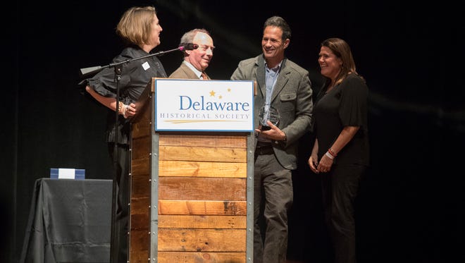 Delaware Historical Society Chair Peg Laird, from left, Delaware Historical Society Interim CEO David Fleming award the 2018 Delaware History Makers award to Dogfish Head Craft Brewery, Inc. founders Sam Calagione and Mariah Calagione Thursday night at the Queen in Wilmington.