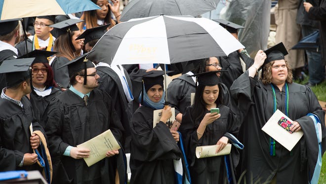 Graduates try to stay dry before the start of the Wesley College Spring Commencement in Dover.  A total of 244 graduated.