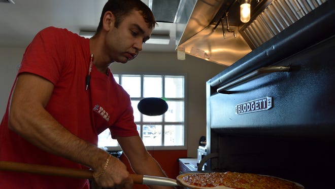 Alex Babayed takes a pizza out of the oven at Just Pizza in Bethany Beach.