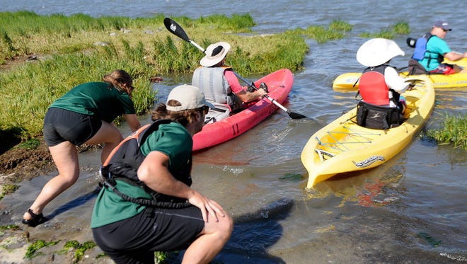 Casey Brotman and Andrew Kleinstauver, Delaware State Park tour guides, help push  kayakers into Rehoboth Bay for an eco-tour around Delaware Seashore State Park in 2016.