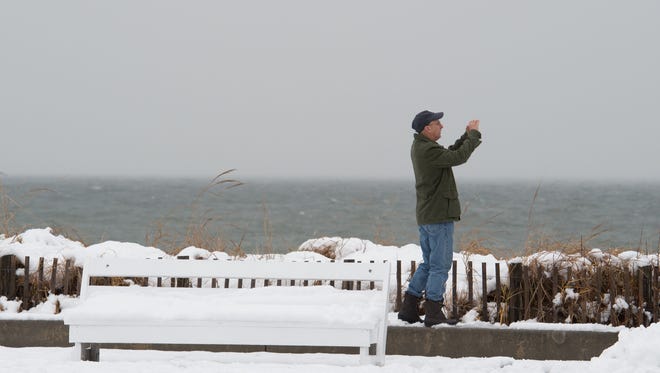 Michael Poniatowski of Baltimore, Md., takes a photo of the snow at Rehoboth Beach.