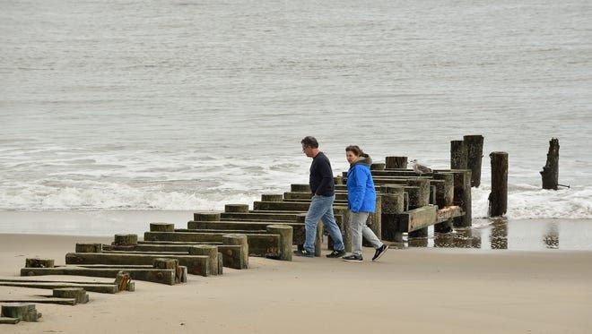 A couple walks over the uncovered storm water outfall pipes at Rehoboth Beach.