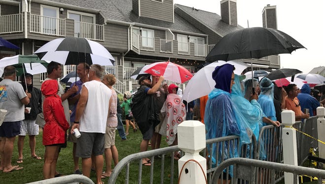 Spectators huddle under umbrellas on the first day of The White Marlin Open at Harbour Island Marina in Ocean City, Md. on Monday, August 7, 2017.