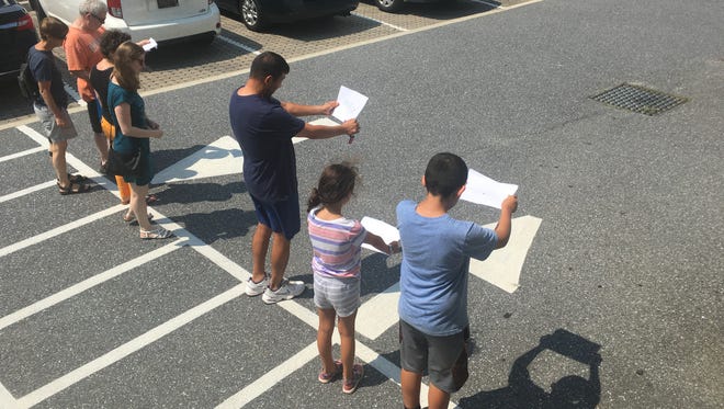 The Desantos family attempts to view the eclipse through a paper with the map of the United States on it at the Worcester County Library in Ocean City on Monday, Aug. 21.