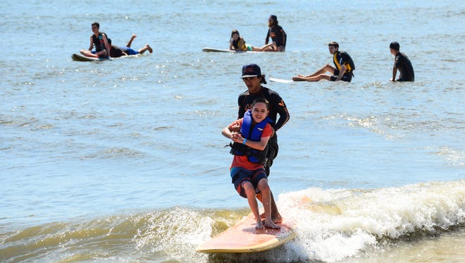 Nikolas Andersen, 12, Dover, De.  gets help with from a volunteer to catch a wave during the Surfers healing tour that helps people living with autism by exposing them to a surfing experience in Ocean City. on August 17, 2016.