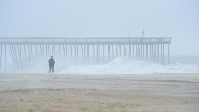 A woman walks across the beach in Ocean City, Md. as Hurricane Maria is off the coast in the Atlantic Ocean on Wednesday, Sept. 27, 2017.