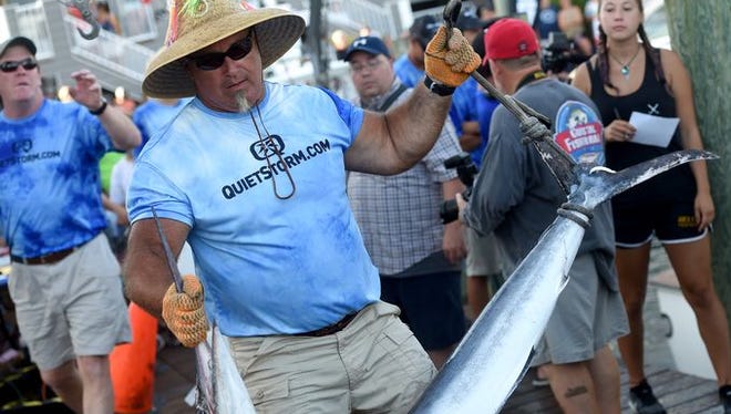 Alex Davis, a weigh master, holds a 63.5-pound white marlin from the White Marlin Open in Ocean City, Maryland.