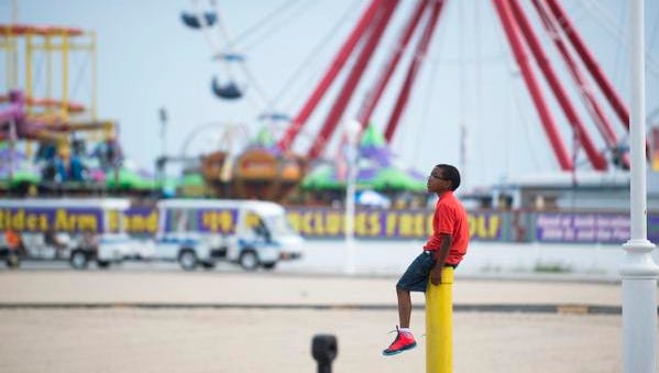 A young boy sits atop a post on a mild afternoon at the Ocean City Boardwalk.