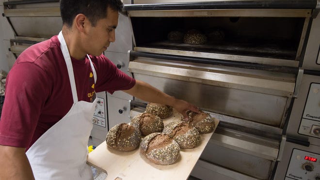 Roni Ramirez, production manager at Old World Breads in Lewes, checks on ancient grain bread baking in their oven.