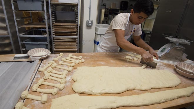 Wilson Ramirez, a baker at Old World Breads in Lewes, cuts dough into smaller sizes to make cinnamon shortys.