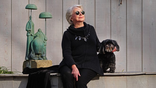 Ellen Roney Hughes sit with her dog Ming next the sculpture by her late husband Gary Hughes at the Rehoboth Art League.