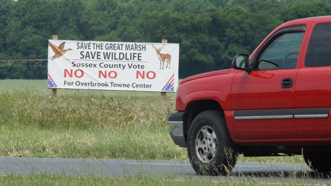 A driver passes a sign, in 2015, at Cave Neck Road and Del. 1 opposing the Overbrook Town Center, a proposed shopping complex north of Lewes.