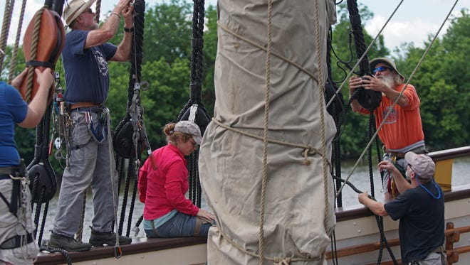 Crew members and volunteers help retie the Kalmar Nyckel main mast shrouds after the mast was put back on board.