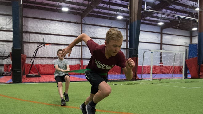 Brandon Boyd (12), left, and Carter Boyd (12) perform a resistance drill during a training session with Sports Specific Training at Slim's Sport Complex in Middletown.