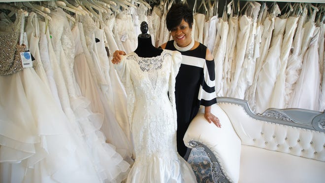Monica Dudley, owner of Bella's YOUnique Bridal Boutique, stands next her wedding dress that she renewed her vows in 10 years after she married her husband of 37 years, Gerry.