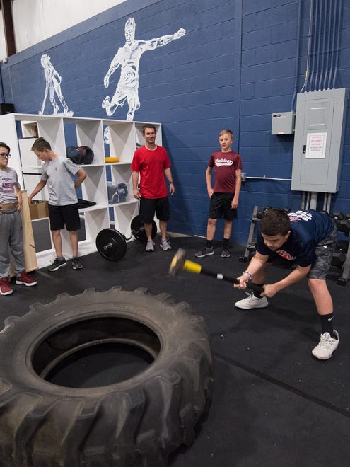Andrew Pierce (12) hits a tire with a sledge hammer during a training session with Sports Specific Training at Slim's Sport Complex in Middletown.