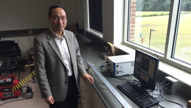 Yuanwei Jin, a University of Maryland Eastern Shore professor, poses beside his patented sensor system. The sensors, shown on far ends of a metal bar, could be used to help detect flaws in underground oil pipes, he suggests.
