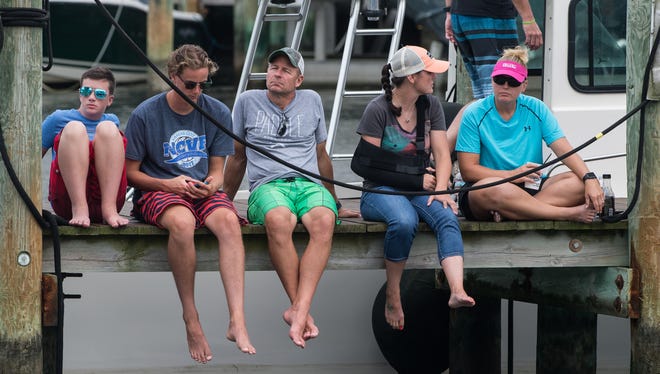 Spectators sit on a dock awaiting the arrival of incoming boats during the White Marlin Open on Friday, Aug. 11, 2017.
