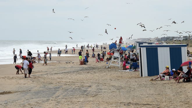 Vacationers lounge on the beach and watch the waves at Rehoboth Beach on Monday.