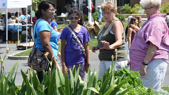 Church gardeners Dottie Outland, right, and Diane Mead talk with Naomi, left, and Malina Alwis from Old Bridge, N.J.