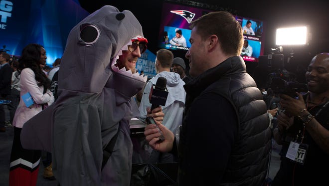 A journalist in a shark costume is interviewed during the Super Bowl Opening Night Monday at Xcel Energy Center.