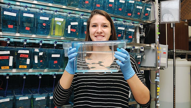 A student displays a tank of fish, part of her undergraduate research project.
