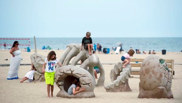 Children play on dinosaur-themed sculptures near the Ocean City Boardwalk.