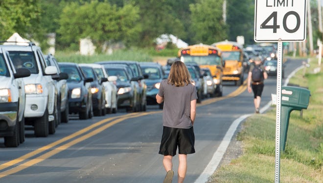 A festival goer walks along Leipsic Road next to a line of traffic at the Firefly Music Festival in Dover.