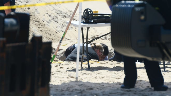 Ocean City Police and Forensics Units are seen in a deep hole that was dug around the area where an unidentified body was found this morning around the 2nd Street beach in Ocean City, Md. on Monday, July 31, 2017.