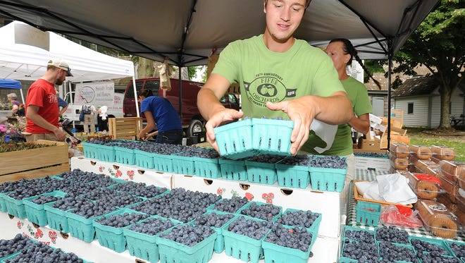 Kyle Brennan from Fifer Orchards puts fresh blueberries out for sale at the Lewes Farmers Market during the 2015 season.
