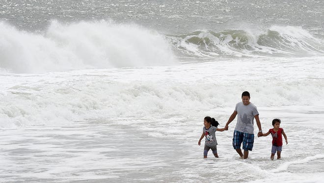 A trio wades in Monday as swimming continues to be banned on Rehoboth Beach.
