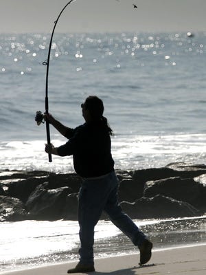 A surf fisherman casts a line on a Delaware beach. As the practice grows more popular, nearby residents say, there have been more conflicts between fishermen and sunbathers.