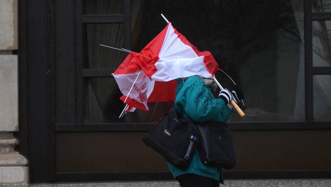 A pedestrian fights the last of her umbrella in the high winds while walking past the Hotel duPont on Monday afternoon.