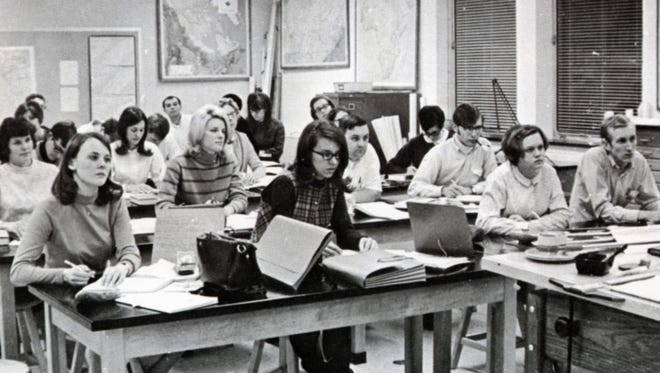1969: SU students sit in a classroom listening intently to a lecture, some taking notes.