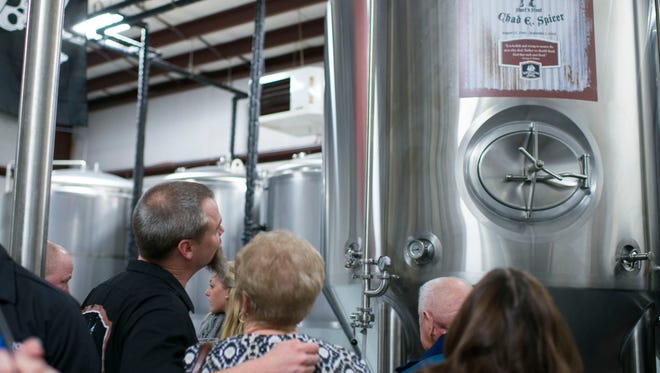 Mispillion River Brewing co-founder Eric Williams, left, looks up at the dedicated fermenter tank alongside Chad Spicer's mother Ruth Ann Spicer in a ceremony at the brewery Thursday, Feb. 26 in Milford.
