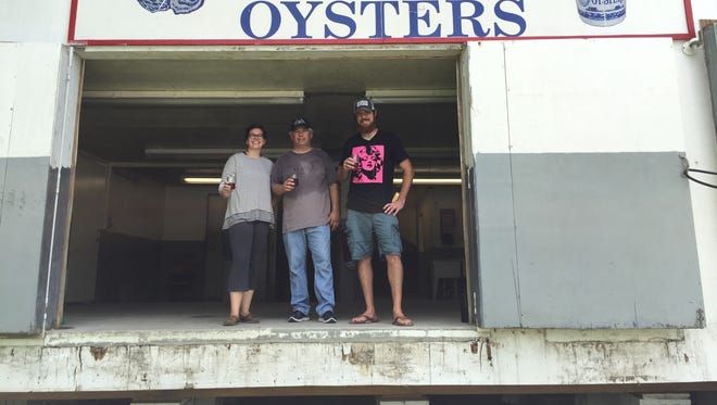 Jenna Chapman (left), Bob Huntley and Josh Chapman stand in front of the Little Bay Seafood Co. sign that will feature prominently in the Black Narrows Brewing Co. interior design.