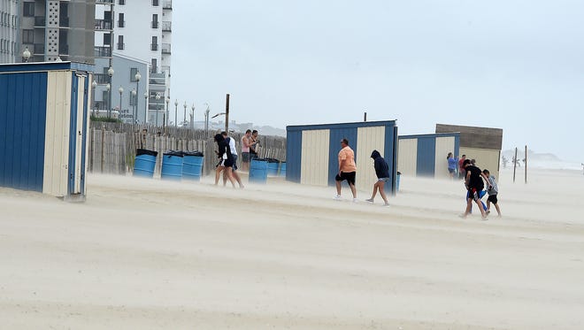 People leave the beach as sand blows at Rehoboth Beach on Saturday, July 29, 2017, as wind-blown sand kept the crowds off the beach and high surf had the water closed by the beach patrol.