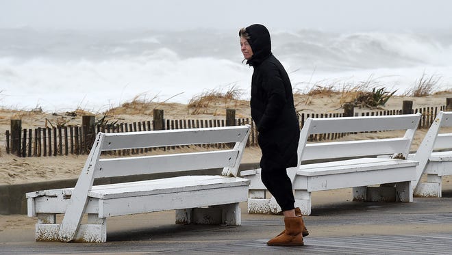 A boardwalk visitor leans into the wind along Rehoboth Beach on Monday.