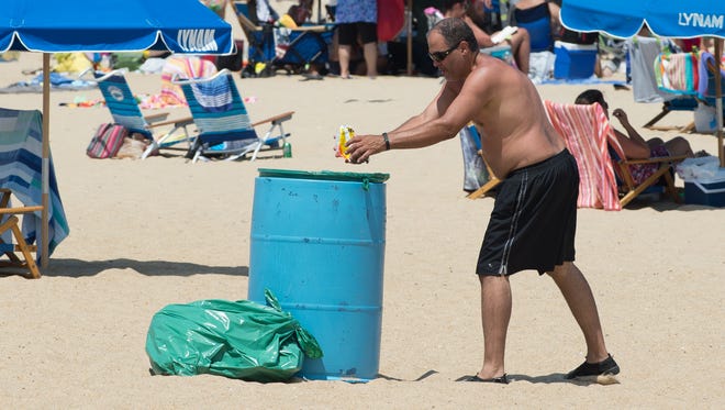 Luis Ortiz of Bushkill, Pa., throws away trash into a trash can on the beach at Rehoboth Beach.