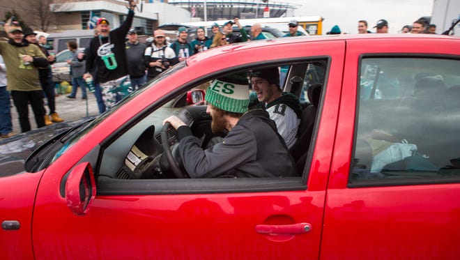 Eagles fans celebrate as people drive their cars over a stuffed vikings animal.