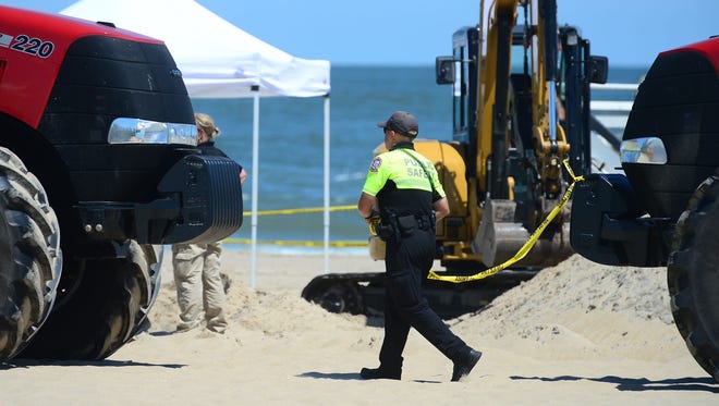 An Ocean City Public Safety Officer puts police tape around the area where an unidentified body was found this morning around the 2nd Street beach in Ocean City, Md. on Monday, July 31, 2017.