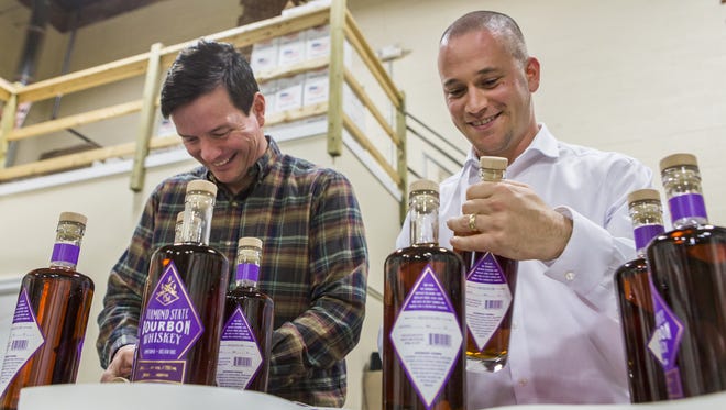 State Rep. Trey Paradee, D-Cheswold,  (left) and Rep. Jeff Spiegelman, R-Clayton, cork and label bottles of Painted Stave's  bourbon whiskey in 2015. The distillery led the push in support of H.B. 373.