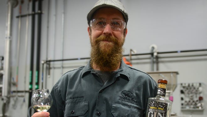 Dogfish Head's lead distiller Graham Hamblett holds a bottle of Mellowdious Gin at the Dogfish Head Distillery on Friday, July 14, 2017.
