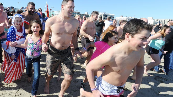 A couple of bare-chested revelers dash toward the Atlantic on Sunday during the 2017 Polar Bear Plunge.