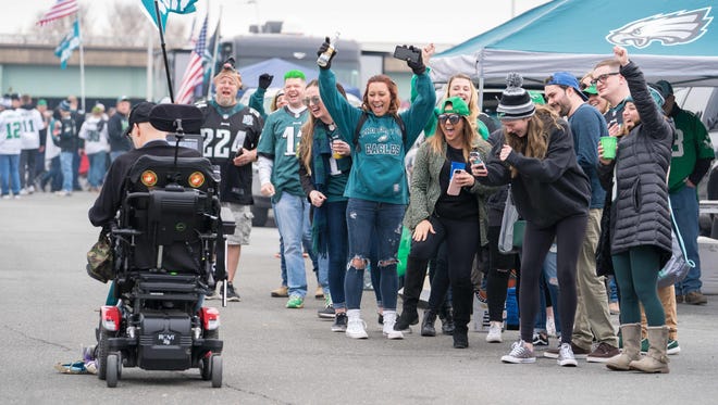 Eagles fans celebrate as people drive their cars and wheelchairs over a stuffed vikings animal.