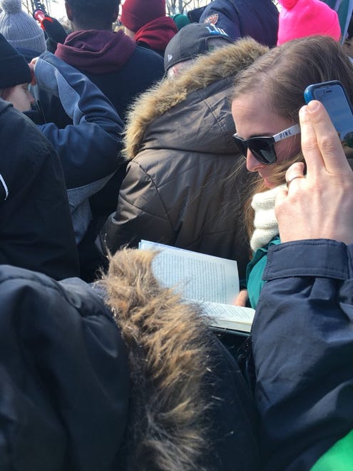 A woman reads a book much to the shock/suprise/disgust of fan around her.