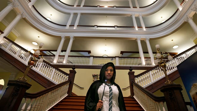 In this Oct. 22, 2016, photo, Celess Leblanc, from the New York City borough of Queens, dresses in costume while attending an annual festival in Philadelphia based on the Harry Potter fantasy series conceived by British author J.K. Rowling, and holds a wand while posing for a photograph inside Chestnut Hill College's St. Joseph Hall in the Chestnut Hill neighborhood of Philadelphia. In 2018, Warner Bros. notified organizers of Harry Potter fan festivals around the U.S. of new guidelines prohibiting any use of names, places or objects from the fantasy series, in an effort to crack down on unauthorized commercial activity at such events. (David Maialetti/The Philadelphia Inquirer via AP)